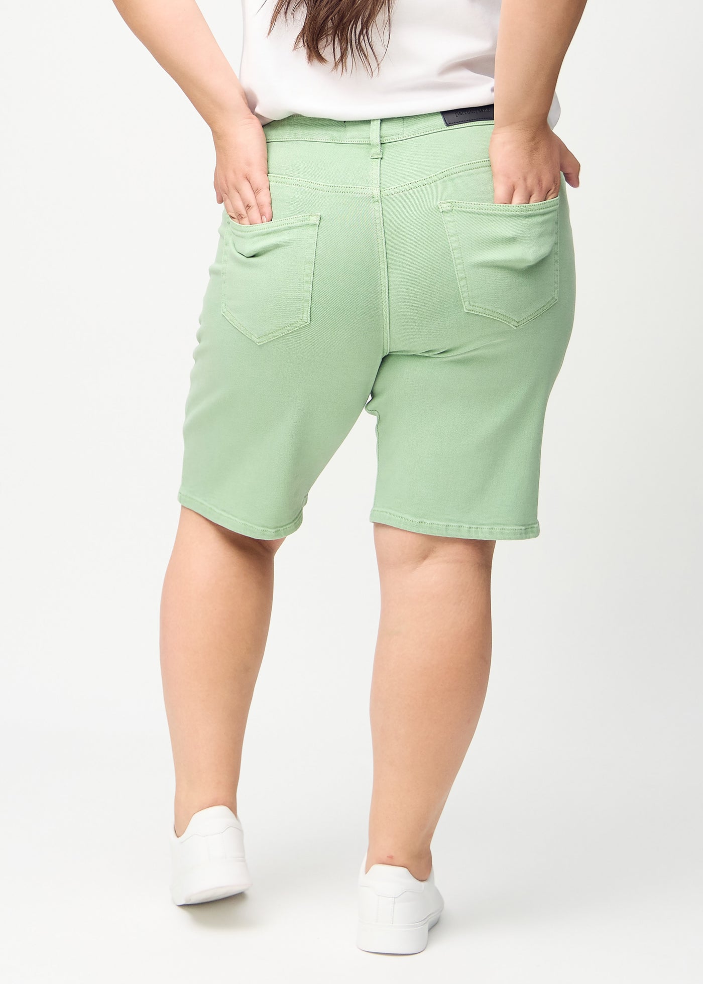 Lysegrønne regular middle shorts set bagfra på en plus-size model, så man kan se hele produktet.