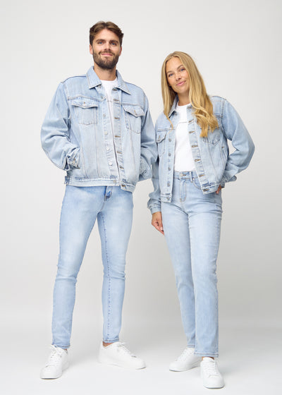 Fuldt billede af unisex lyseblå denim jakke, set forfra på herre og dame model, hvor man ser knapper og lommer i farven Waves.